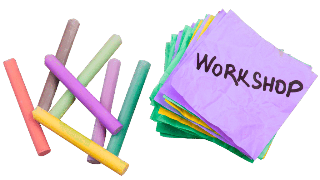 Colourful chalk sticks and a heap of colourful post-it notes, with the word workshop written on the top one
